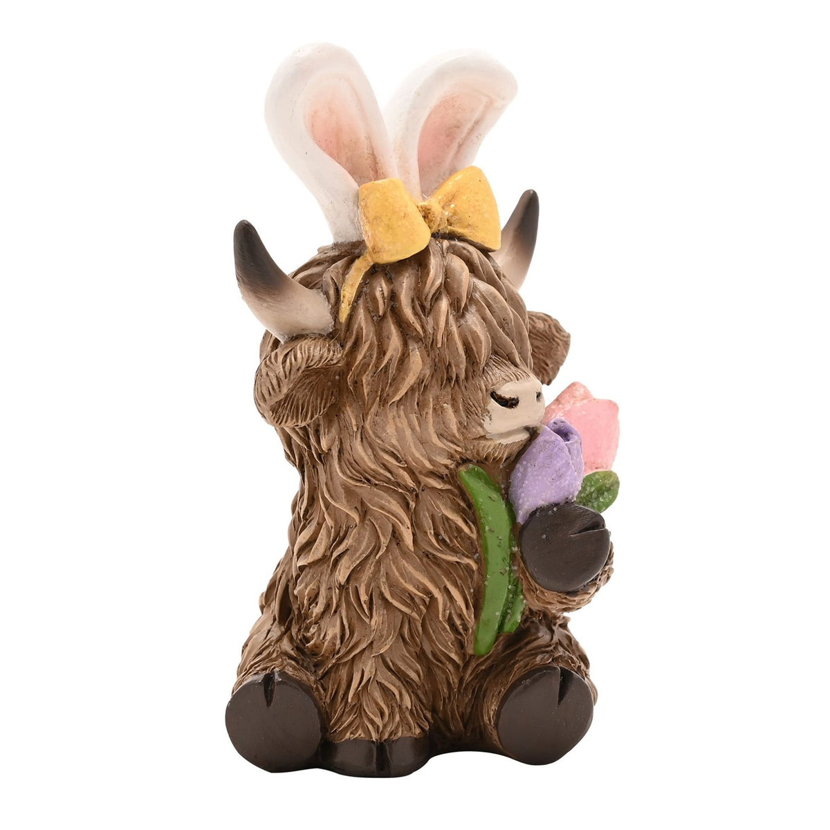 Sitting Highland Cow Easter Bunny resin decoration in brown, shaggy coat, white bunny ears with yellow bow, holding pink and lilac tulips, on a plain white background.