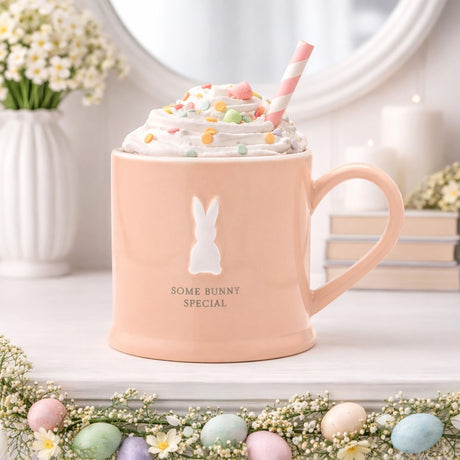 Pink ceramic mug with raised white bunny silhouette and "Some Bunny Special" text, glossy finish, shown with whipped cream, sprinkles and striped straw.