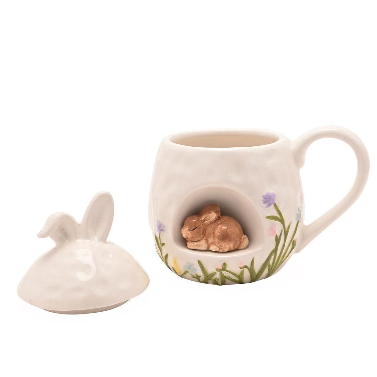 White ceramic mug with lid, featuring a 3D sleeping bunny nestled in a front nook, bunny-ear lid topper, and painted floral grass border, shown on a plain background.