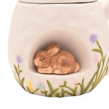 Close-up of the white ceramic Easter mug showing a 3D sleeping bunny nestled in an arched front nook, with hand-painted grass and pastel flowers along the base.