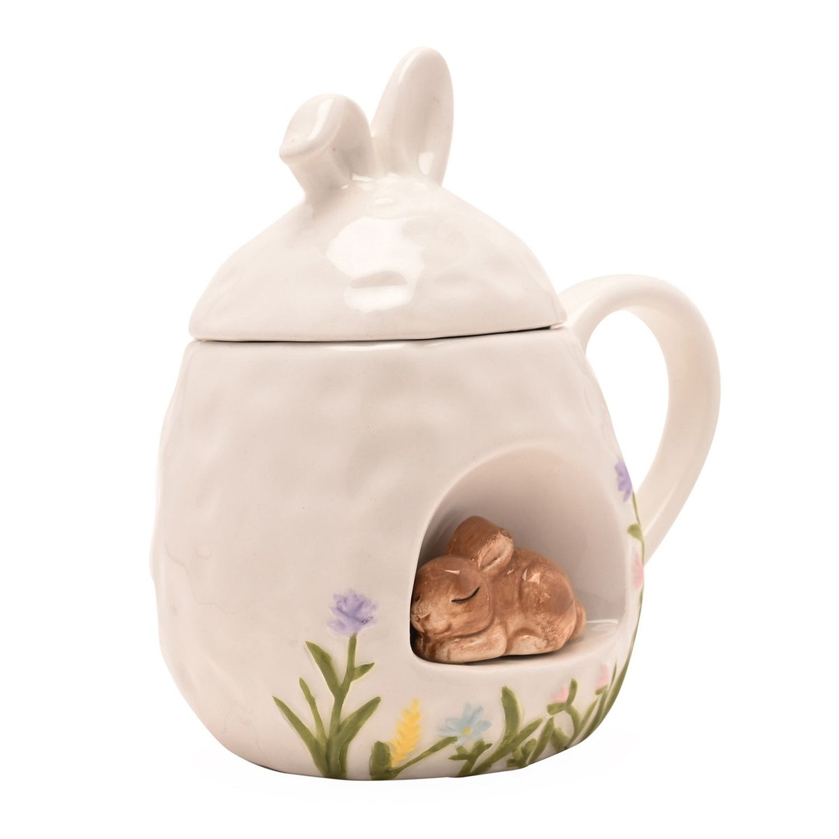 White ceramic mug with bunny-ear lid and a 3D sleeping bunny nestled in a front nook, painted with grass and pastel floral details, shown on a plain background.