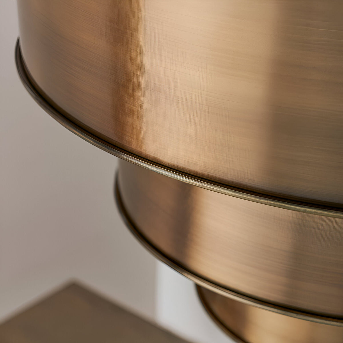Close-up of the Endon Carlwick tiered pendant showing stacked cylindrical shades in aged brass with a warm, brushed metallic finish.