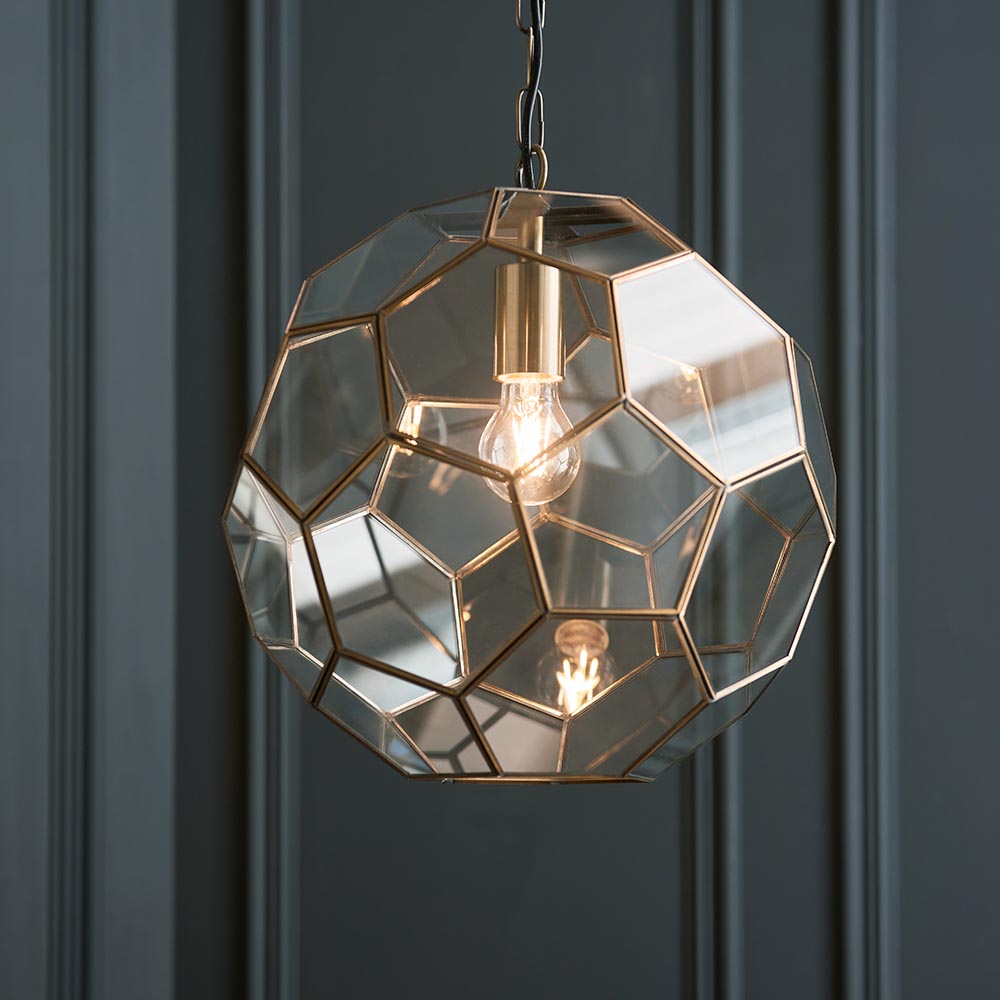 Endon Carldon hexagonal pendant light in antique brass with clear faceted glass panels and decorative chain, lit E27 bulb, against a dark panelled wall.