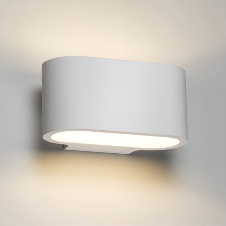 The Curved Up And Down Plaster Wall Light 180mm casts gentle, ambient lighting on a neutral-colored wall, cultivating a warm and inviting atmosphere.