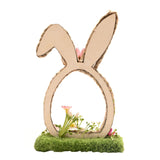 Faux flower bunny ears decoration with natural braided egg-shaped loop, tall upright ear and folded ear, pink faux daisy accent and mossy base, on a plain white background.