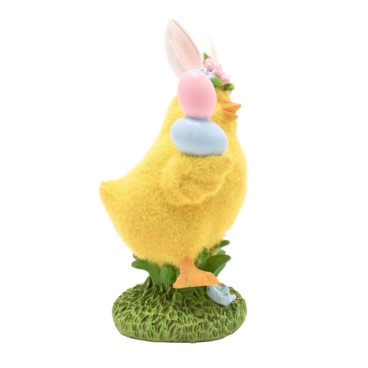 Yellow resin Easter chick figurine with bunny ears and floral band, holding pink and blue eggs, fuzzy textured body on a green grass base, plain white background.