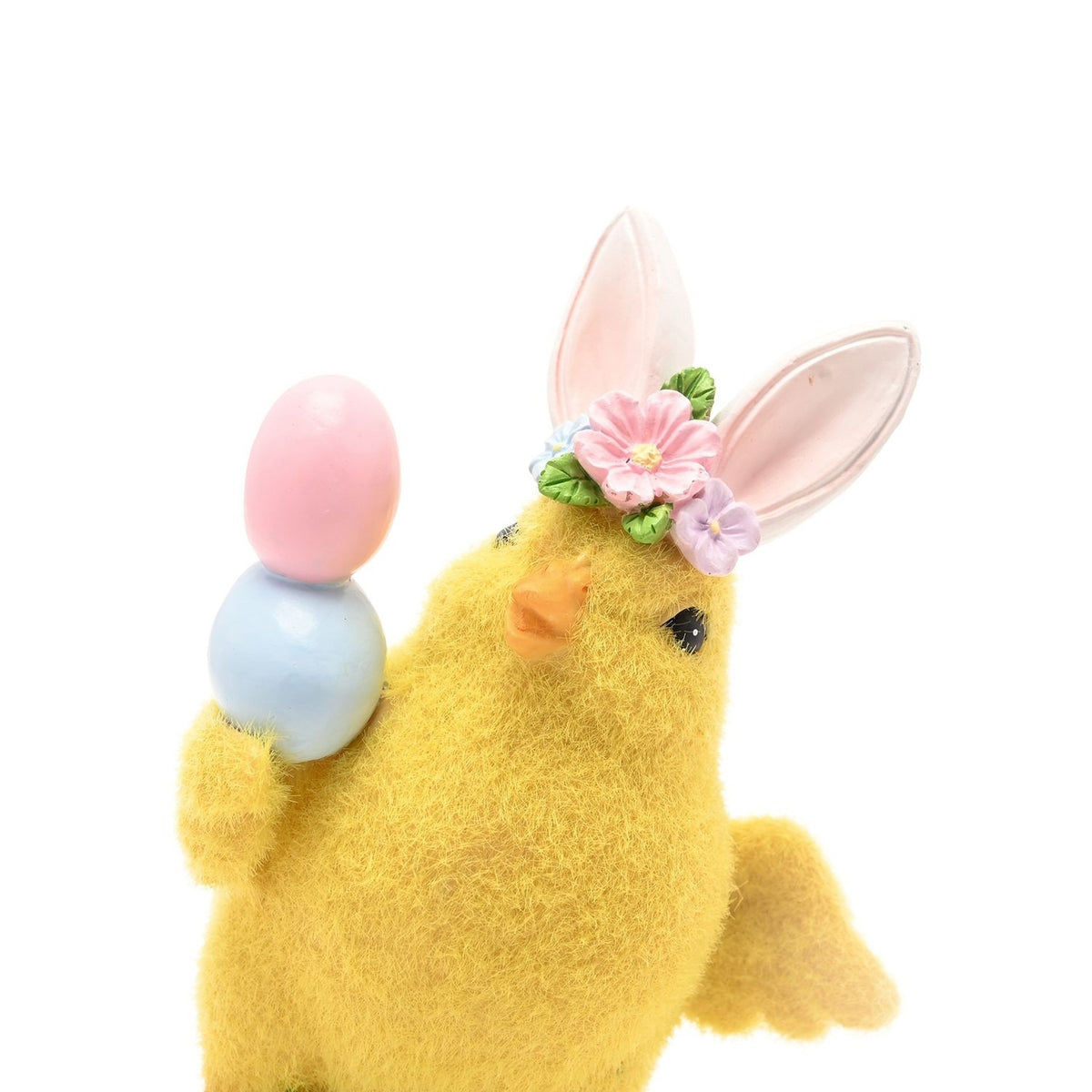 Yellow resin Easter chick figurine with bunny ears and floral band, balancing a pink and blue egg in its wing, fuzzy finish, on a white background.