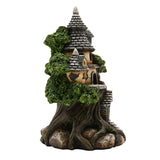 LED Treehouse Resin Light-Up Decoration, 19.8cm, depicting a turreted stone cottage with grey spired roofs and green foliage set into a tree trunk, on a plain white background.