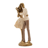 Resin figurine of a couple embracing while holding a baby, with cream textured clothing and gold-tone skin and hair, set on a gold oval base against a plain white background.