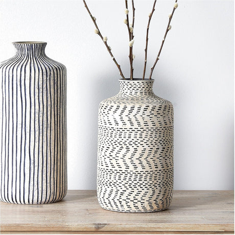 Atouk 28cm ceramic vase in natural and black with textured Aztec-style chevron and dash pattern, holding dried branches, beside a striped vase on a wooden surface.