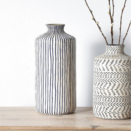 Bude Blue & White Stoneware Stripe Design Vase, 36cm, cylindrical ceramic form with narrow vertical stripes, shown on a wood surface beside a patterned vase with branches.