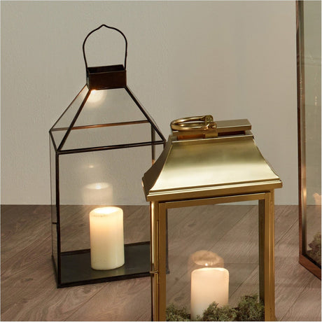 Antique Brass & Glass Lantern, 49cm, with a peaked glass top and brass frame, shown beside a smaller black-framed lantern, each holding a pillar candle on a wooden floor.