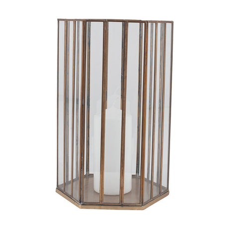 Hexagonal glass lantern with vertical brass frame bars and a white pillar candle inside, shown on a plain white background.