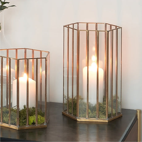 Shiny Brass & Glass Hexagonal Large Lantern, 31cm, shown on a dark sideboard with a lit pillar candle and moss detailing, glass panels framed in antique brass.