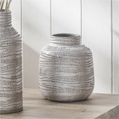 Alina Matt White Stoneware Dot Design Vase - 20cm with rounded body, narrow neck, and textured dotted pattern, shown on a wooden surface against a white panelled wall.