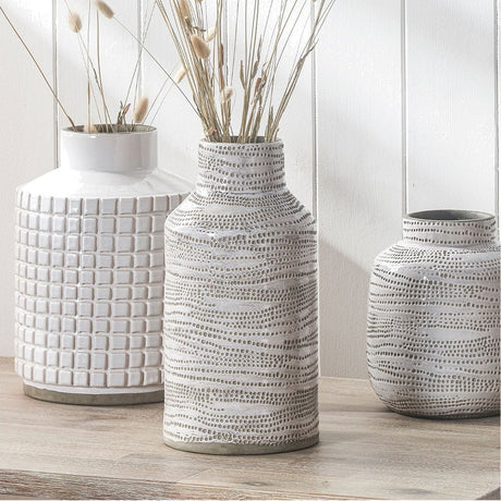 Alina Matt White Stoneware Dot Design Vase, 30cm, tall cylindrical ceramic vase with textured dot pattern, shown with dried grasses beside similar patterned vases on a wooden surface.