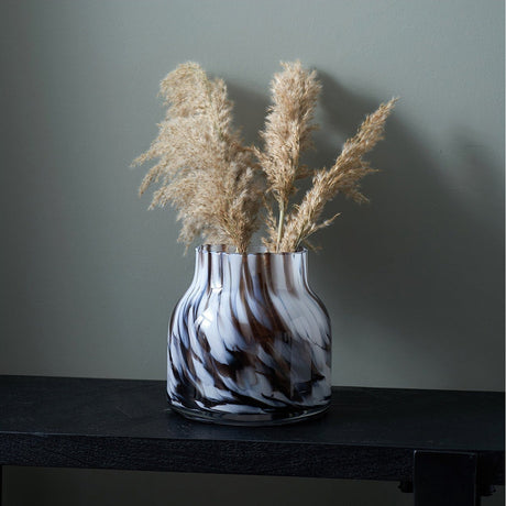 Brown & White Tortoiseshell Glass Vase, 22cm, holding dried pampas grass on a black console table against a muted grey wall.