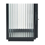 Close-up of a black iron candle lantern with vertical ribbed glass panels, a black metal frame, and visible clasp, on a plain white background.