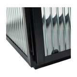 Close-up corner detail of a black iron candle lantern with vertical ribbed glass panels, showing the metal frame joints against a plain white background.