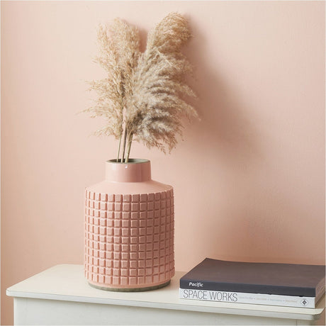 Malone Apricot Stoneware Design Vase, 29cm, with a textured grid pattern, holding dried pampas grass on a white sideboard against a pink wall.