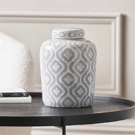 Celia Grey & White Ceramic Geo Pattern Lidded Ginger Jar, 25cm, with quatrefoil pattern, shown on a dark round side table in a living room setting.
