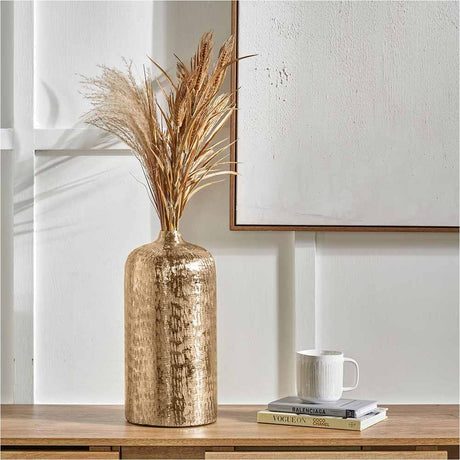 Gold Aluminium Hammered Vase, 38cm, with dried pampas grass and wheat stems, styled on a wooden sideboard beside books and a mug.