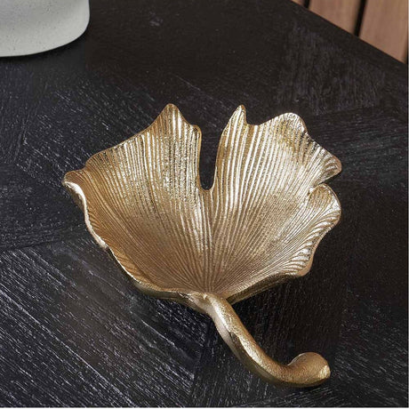 Gold aluminium Gingko Leaf trinket bowl, 17cm, with ridged veined texture and curved stem handle, shown on a dark wood surface.