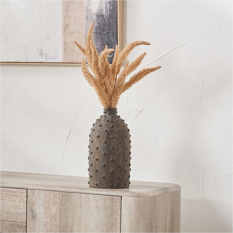 Kali Textured Dot Grey Stoneware Vase, 31cm, with a bulbous studded body holding dried pampas grass stems, shown on a light wood sideboard against a white wall.