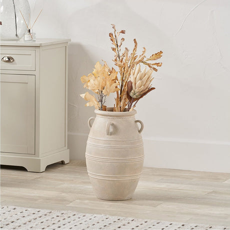 Grey Wash Fibrestone Decorative Ribbed Vase with side handles, 46cm, holding dried foliage in a living room beside a light grey cabinet.