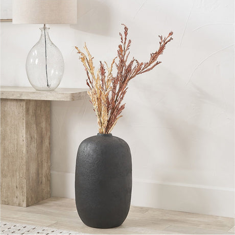 Matt Black Fibrestone Decorative Vase, 53cm tall with textured finish, holding dried foliage, styled on the floor beside a console table in a living room.