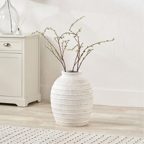 White Wash Fibrestone Decorative Ribbed Large Vase, 49cm, with branch stems, styled on a wooden floor beside a cream cabinet in a living room.