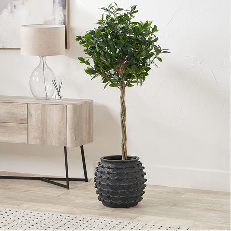 Black Bobble Fibrestone Decorative Large Planter, 39cm, round textured black composite pot holding an artificial tree, shown beside a wooden sideboard in a living room setting.