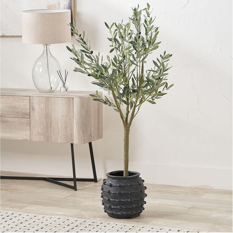 Black Bobble Fibrestone Decorative Planter, 29cm, with textured bobble surface, holding an artificial olive tree in a bright living room beside a wooden sideboard.