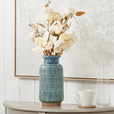 Theano Dot Design Blue Glaze Vase, 31cm ceramic vase with textured dot pattern, holding cream magnolia stems on a console table beside a mug and glass vase.