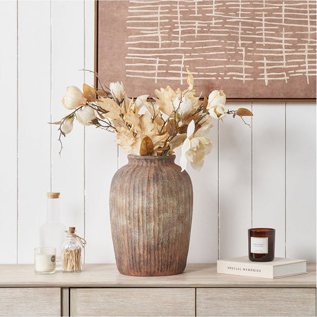 Rustic brown fibrestone vase, 37cm, with vertical ribbed texture, styled with cream faux flowers on a wooden sideboard against a white panelled wall.