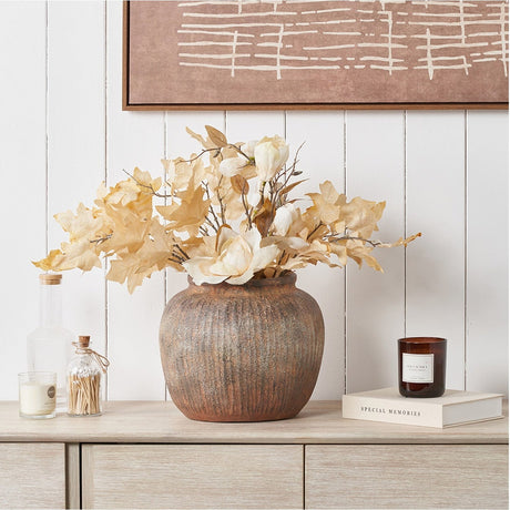 Rustic Brown Fibrestone Vertical Ribbed Decorative Vase, 29cm, holding dried florals and foliage on a wooden sideboard beside candles and books.