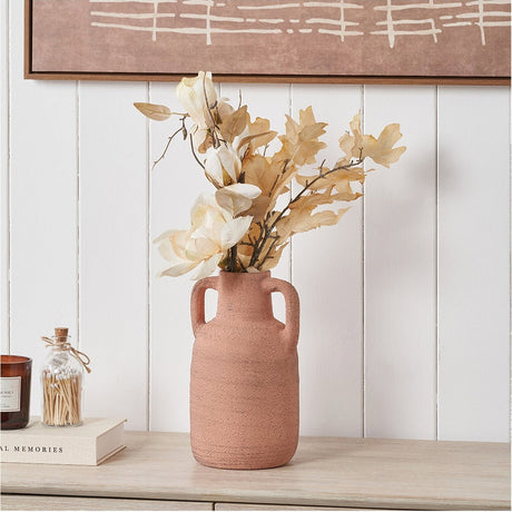 Terracotta textured ceramic vase with two handles, 28cm, holding dried cream and beige stems on a wooden sideboard against a white panelled wall.