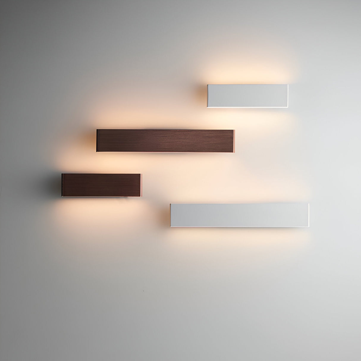 Endon Ambrose wall lights arranged on a pale wall in matt white and dark bronze finishes, each rectangular fitting casting a warm up-and-down glow.