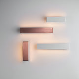 Endon Ambrose matt white LED wall lights arranged with copper-finish fittings on a pale wall, casting warm up-and-down glow in a modern layout.