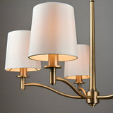 Close-up of Endon Castwell pendant light showing three vintage white fabric shades on curved matt antique brass arms against a grey background.