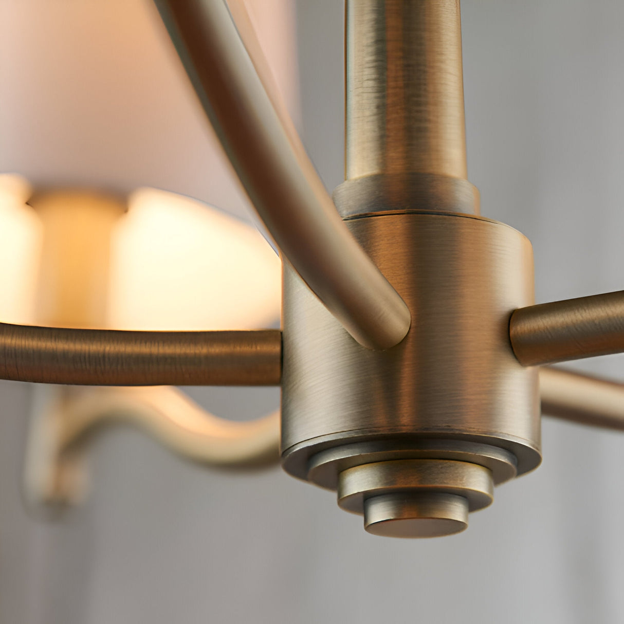 Close-up of the Endon Castwell 5 Light Pendant showing its matt antique brass central hub, curved arms, and a glowing vintage white faux silk shade.