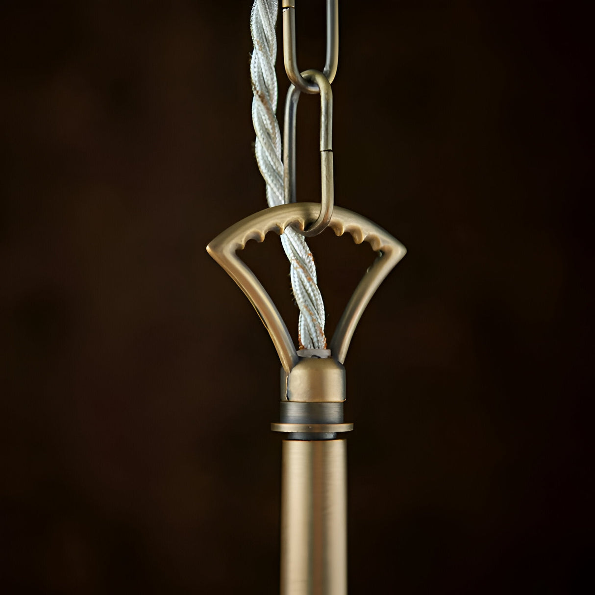 Close-up of the Endon Castwell pendant's antique brass suspension loop, chain link, and grey twisted fabric flex against a dark background.