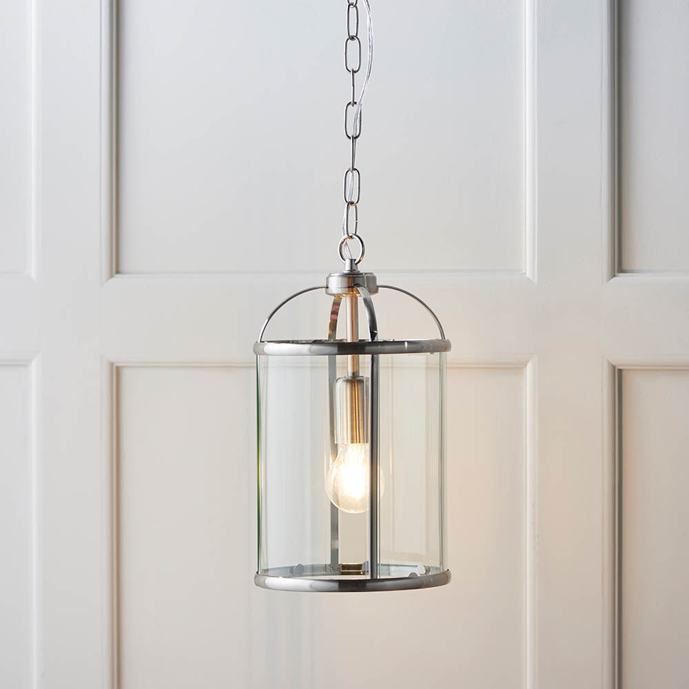 Endon Caldbury lantern-style pendant light in nickel with clear glass panels and an E27 filament lamp, hung from a chain against white panelled walls.