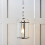 Endon Caldbury lantern-style pendant light in nickel with clear glass panels and an E27 filament lamp, hung from a chain against white panelled walls.