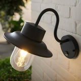 Endon Bevfield fisherman-style outdoor wall light in textured black with clear glass diffuser, lit bulb and built-in PIR sensor, mounted on a white brick wall.