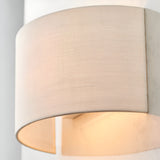 Close-up of the Endon Castmere wall light in white, showing its semi-circular linen shade on a steel frame casting a soft downward glow.