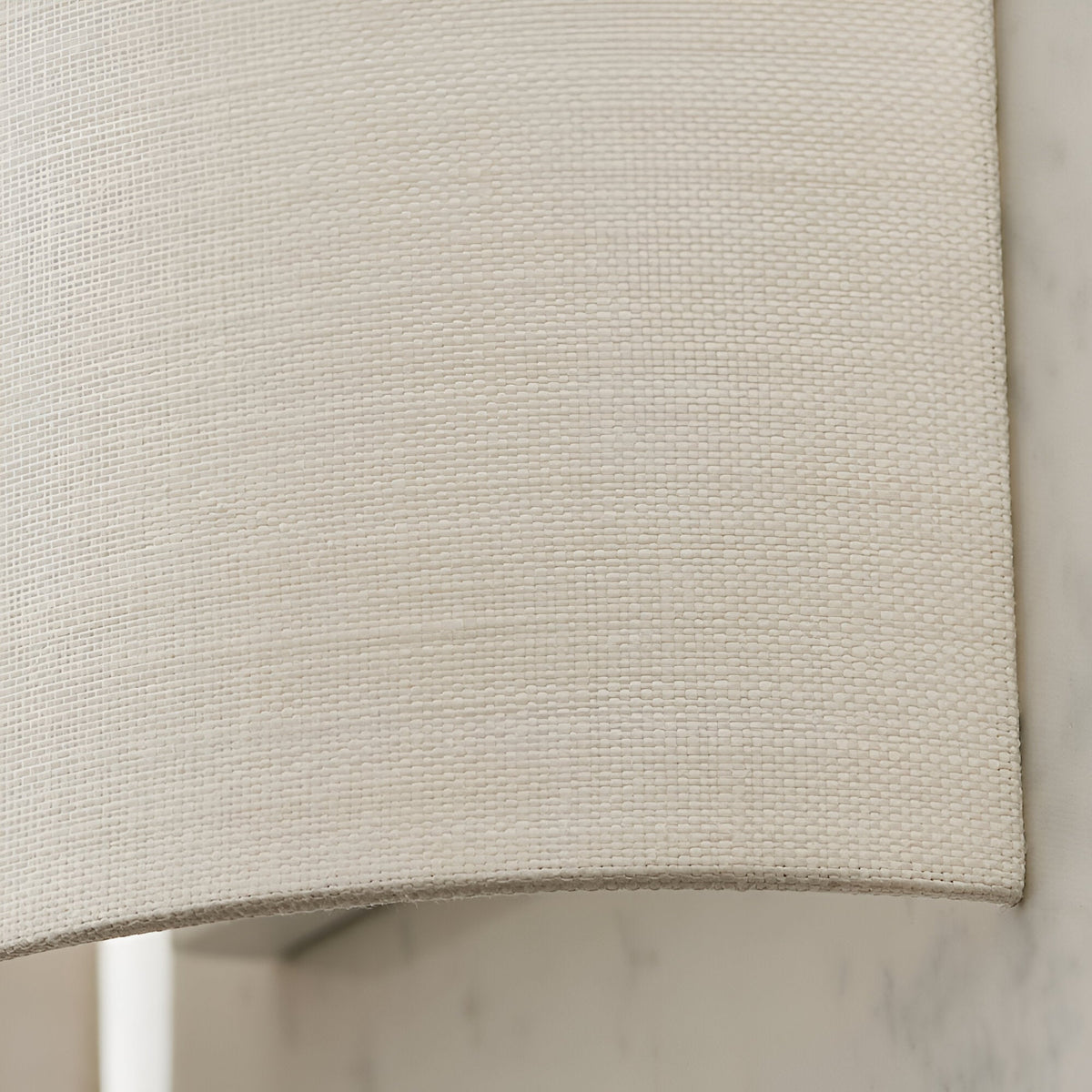 Close-up of the Endon Castmere wall light's semi-circular white linen shade, showing the woven fabric texture and curved lower edge against a pale wall.
