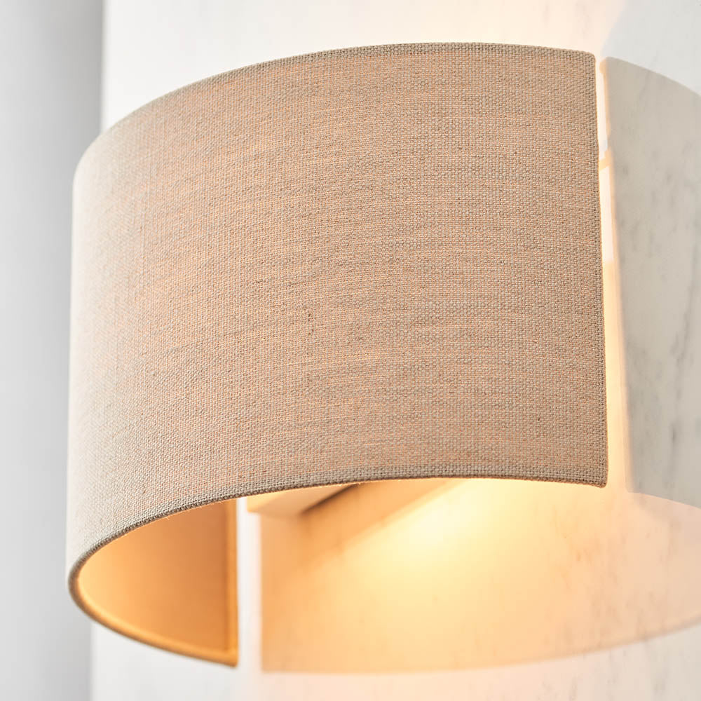 Endon Castmere semi-circular wall light in natural linen on a steel frame, illuminated to cast a soft downward glow against a pale wall.