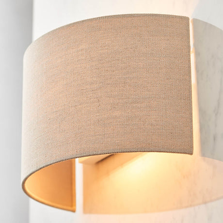 Endon Castmere semi-circular wall light in natural linen on a steel frame, illuminated to cast a soft downward glow against a pale wall.
