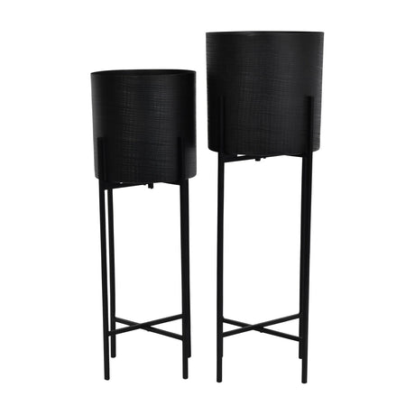 Libra Interiors Etched Iron Set of 2 Floor Standing Planters in matt black, cylindrical pots with cross hatch texture on slim four leg stands.